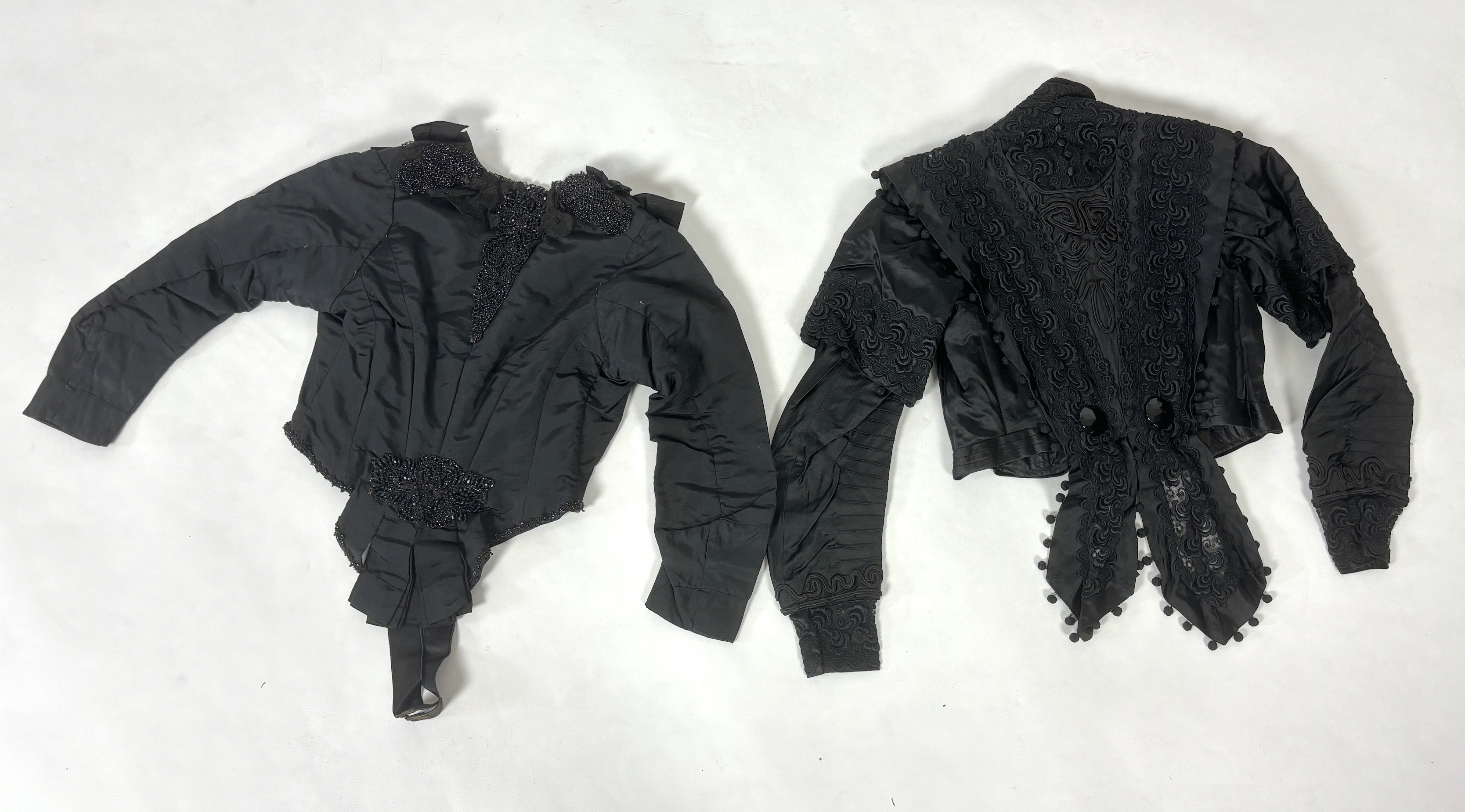 Two lady's Victorian black satin and lace, bead trimmed bodices, together with a black lace cape, a black satin cape, a small collection of coloured feathers and a child’s white worked pinafore